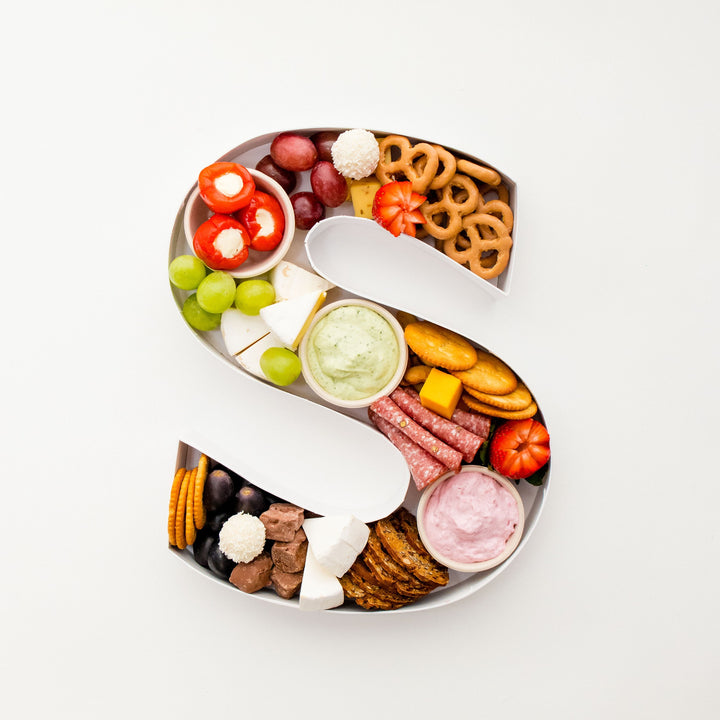 Charcuterie-filled letter S with cheeses, cured meats, dips, fruit and crackers