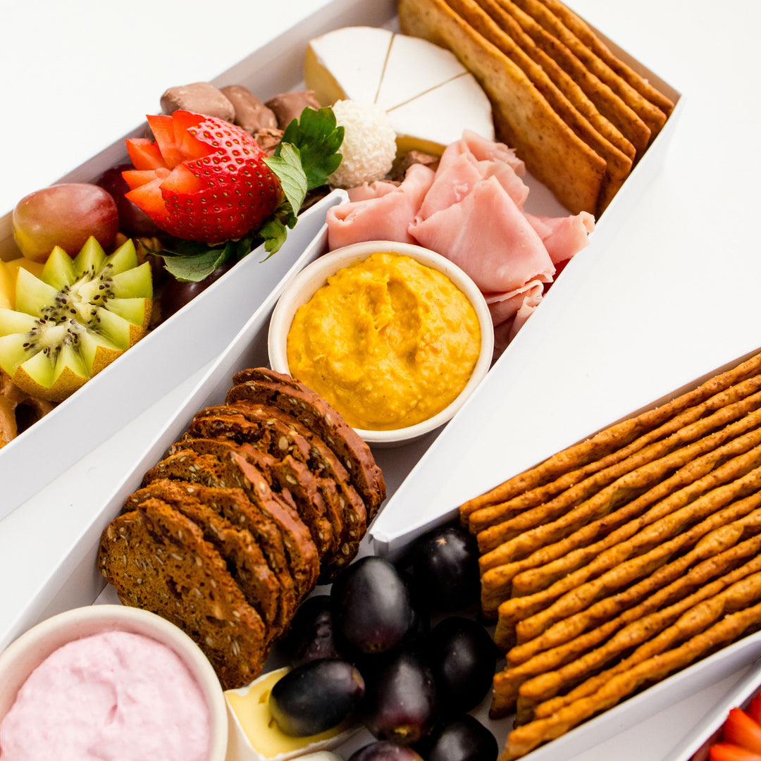 Close-up of cheeses, crackers, fruit and dips in a charcuterie letter